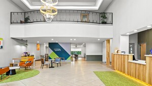 A spacious lobby with a reception desk, seating area, and a staircase leading to an upper level.