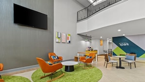 A modern lobby with orange and brown chairs, a flat-screen TV, and a 'spark' sign on the wall.