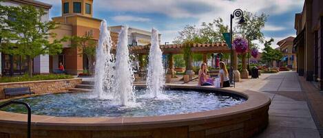 A fountain with multiple water jets in a circular basin, surrounded by a stone walkway.
