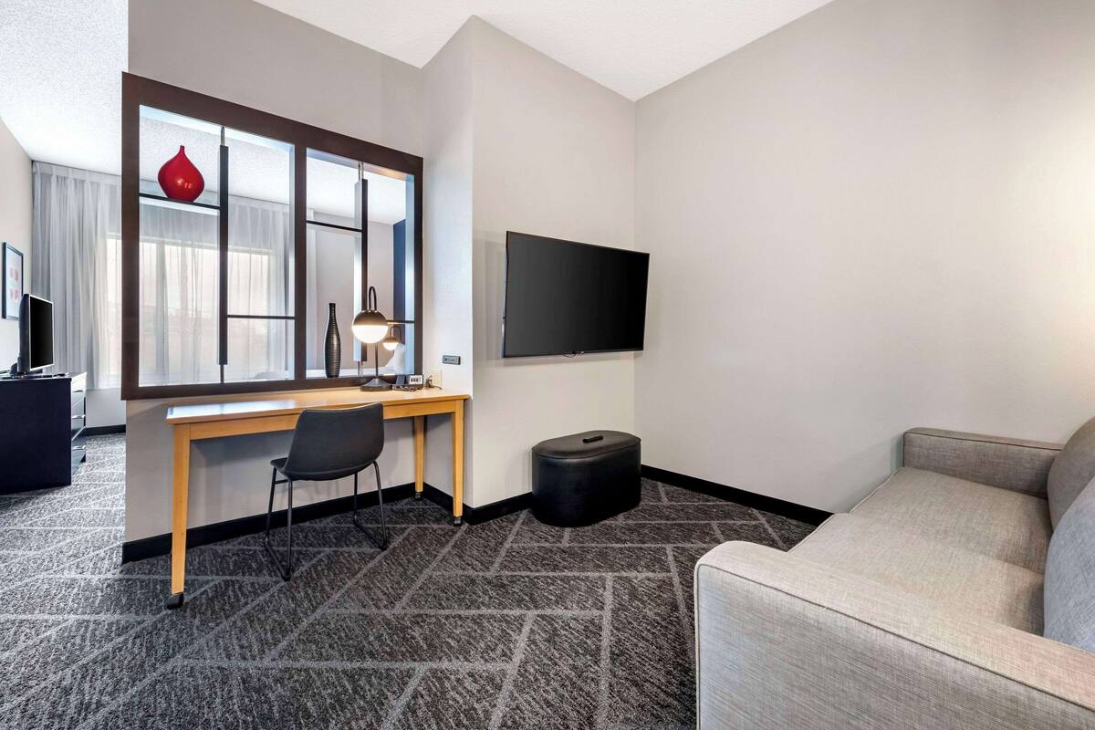 Habitación de hotel con escritorio, silla, televisión y sofá.