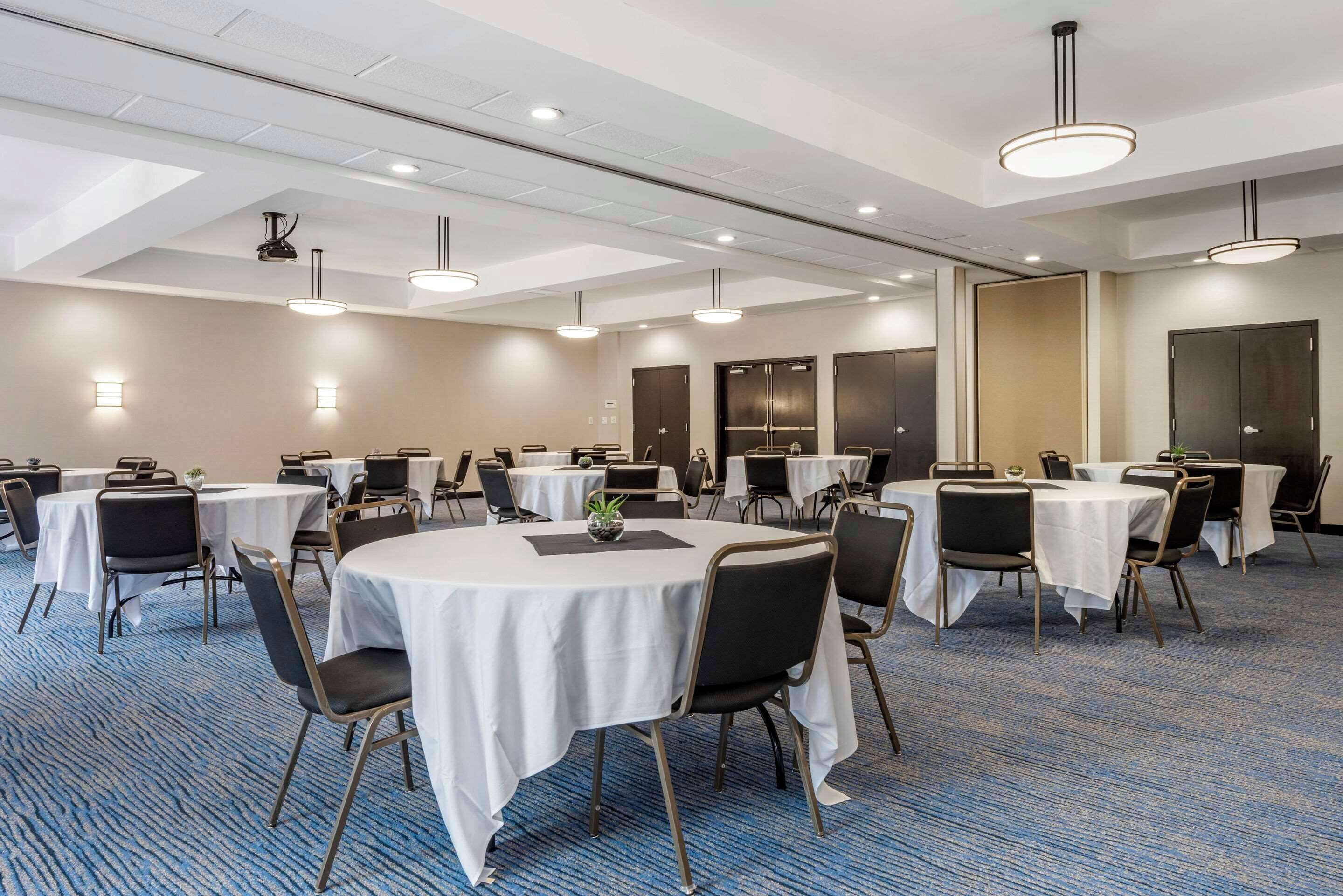 A conference room with round tables, chairs, and ceiling lights.