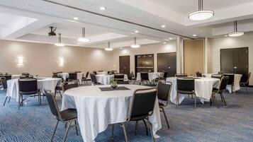 A conference room with round tables, chairs, and ceiling lights.