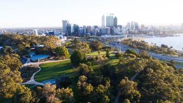 An aerial view of a city with a prominent skyline, a large park with pathways, and a body of water.