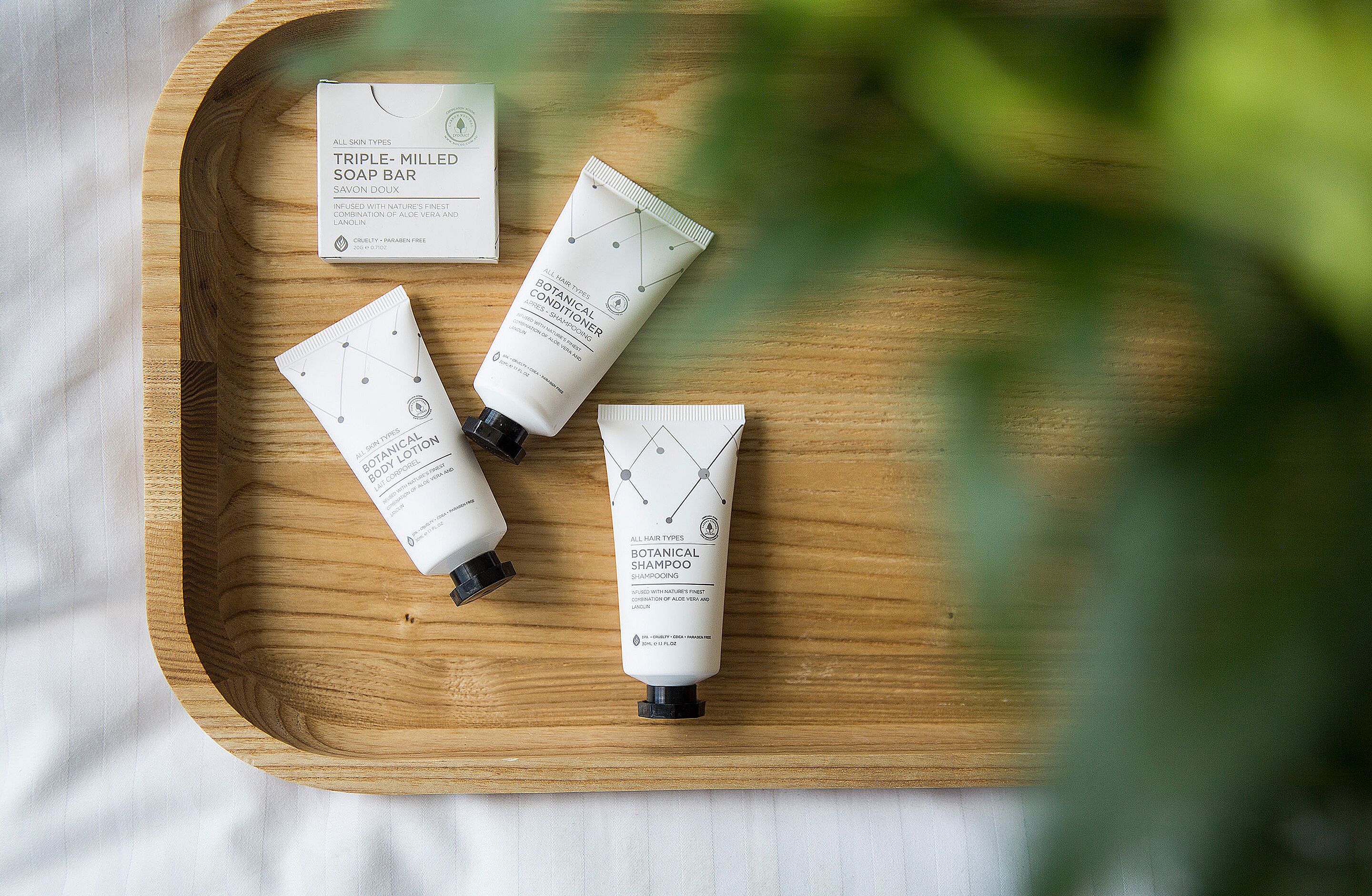 A wooden tray with three skincare products and a box on a white surface.