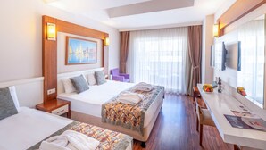 A hotel room with two beds, a desk with a flat-screen TV, a painting on the wall, and a window with curtains. - Hotel Viking Star (Kemer)