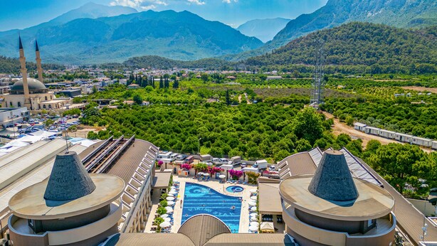 A hotel with a swimming pool, a mosque, and mountains in the background. - Hotel Viking Star (Kemer)