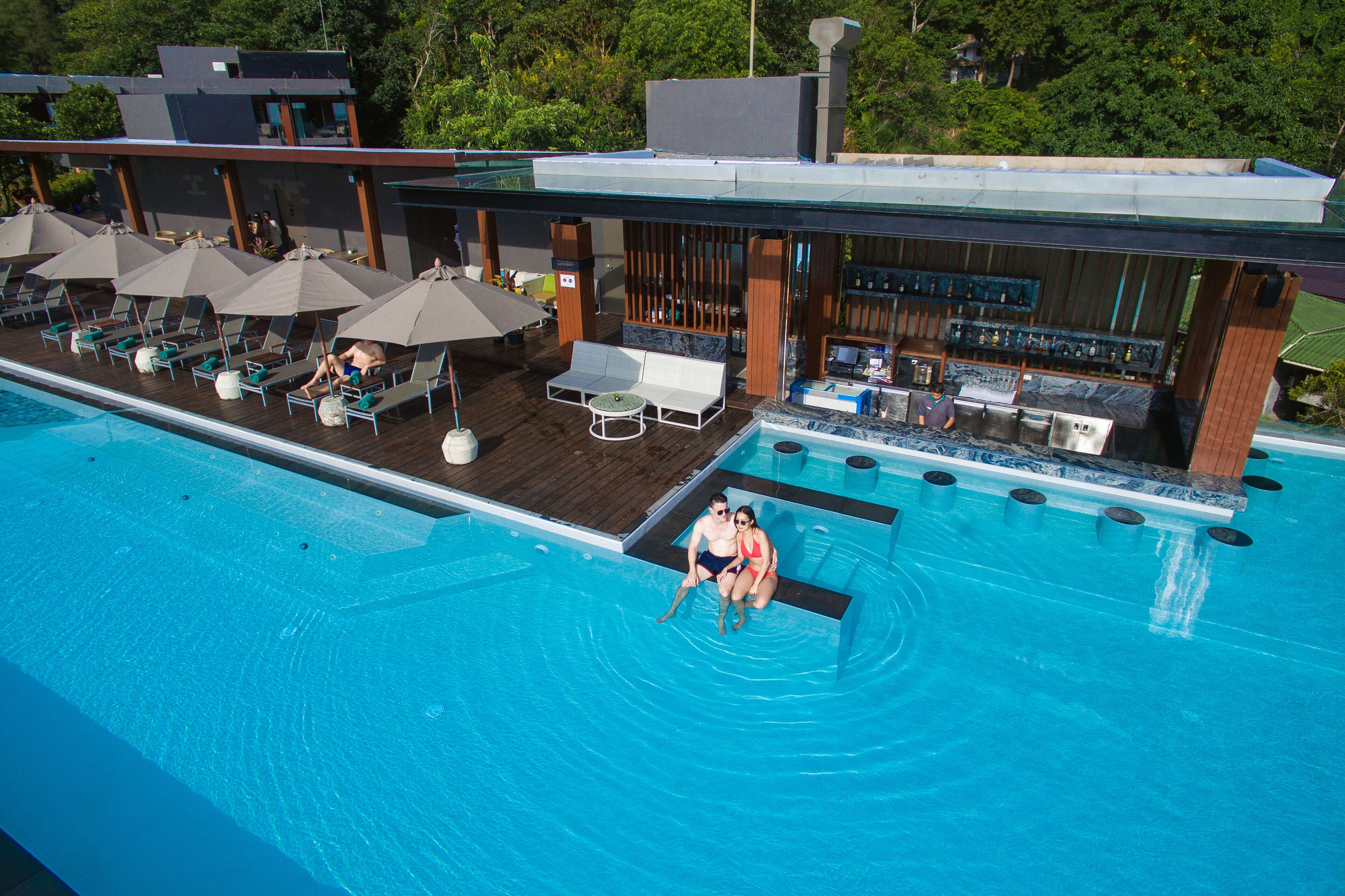 A pool area with lounge chairs, umbrellas, and a bar.