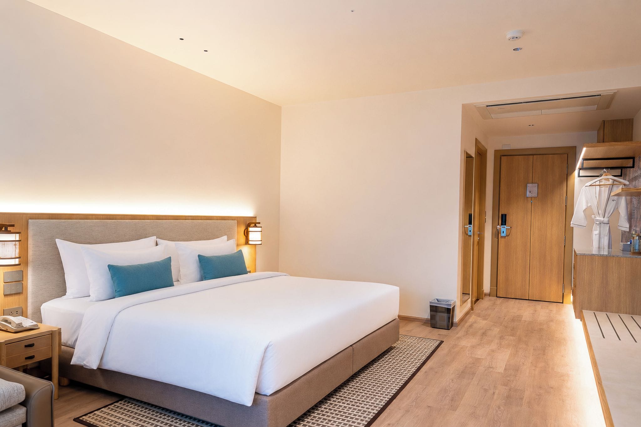 Una habitación de hotel con una cama grande, mesitas de noche, un armario y un baño.