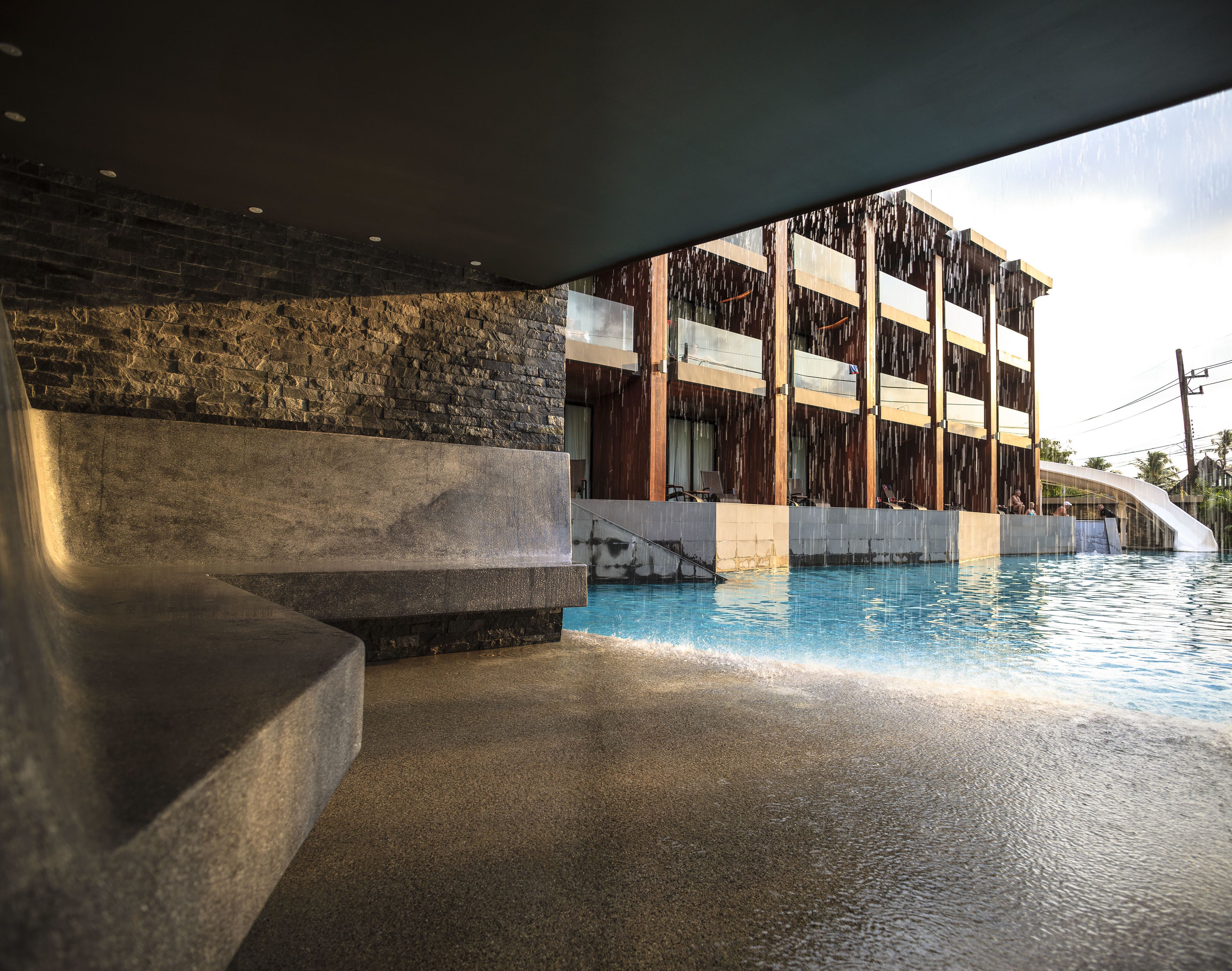 A modern building with a pool, stone steps, and a view of the sky.