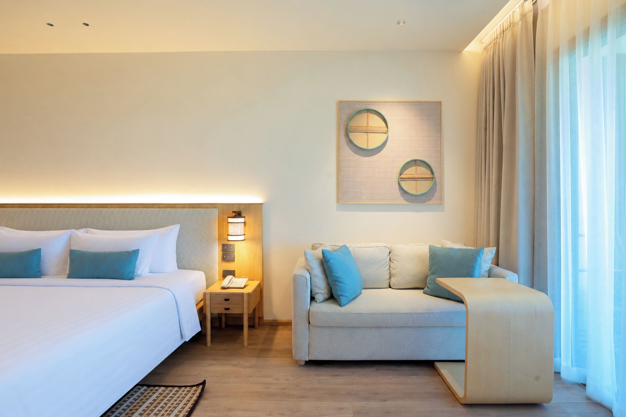 Ein Hotelzimmer mit einem Bett, einem Sofa, einem Nachttisch und einem Wandbild.