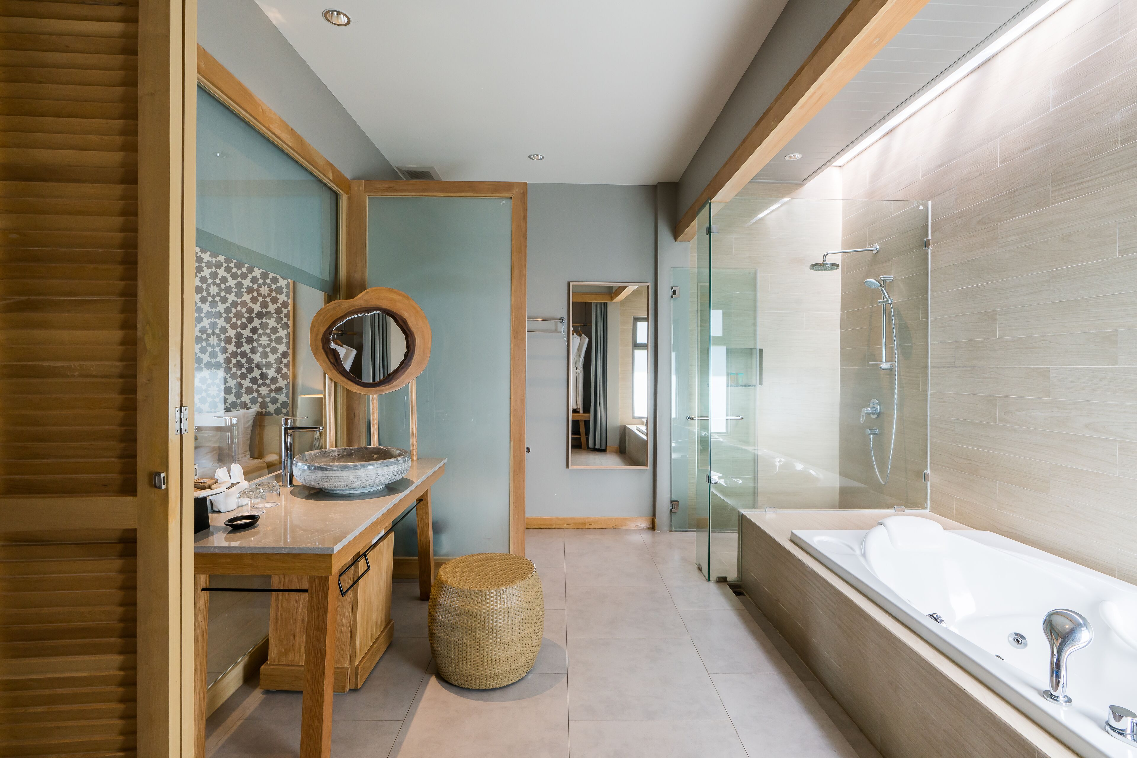 Un baño moderno con un tocador de madera, un espejo grande, una cabina de ducha de vidrio y una bañera.