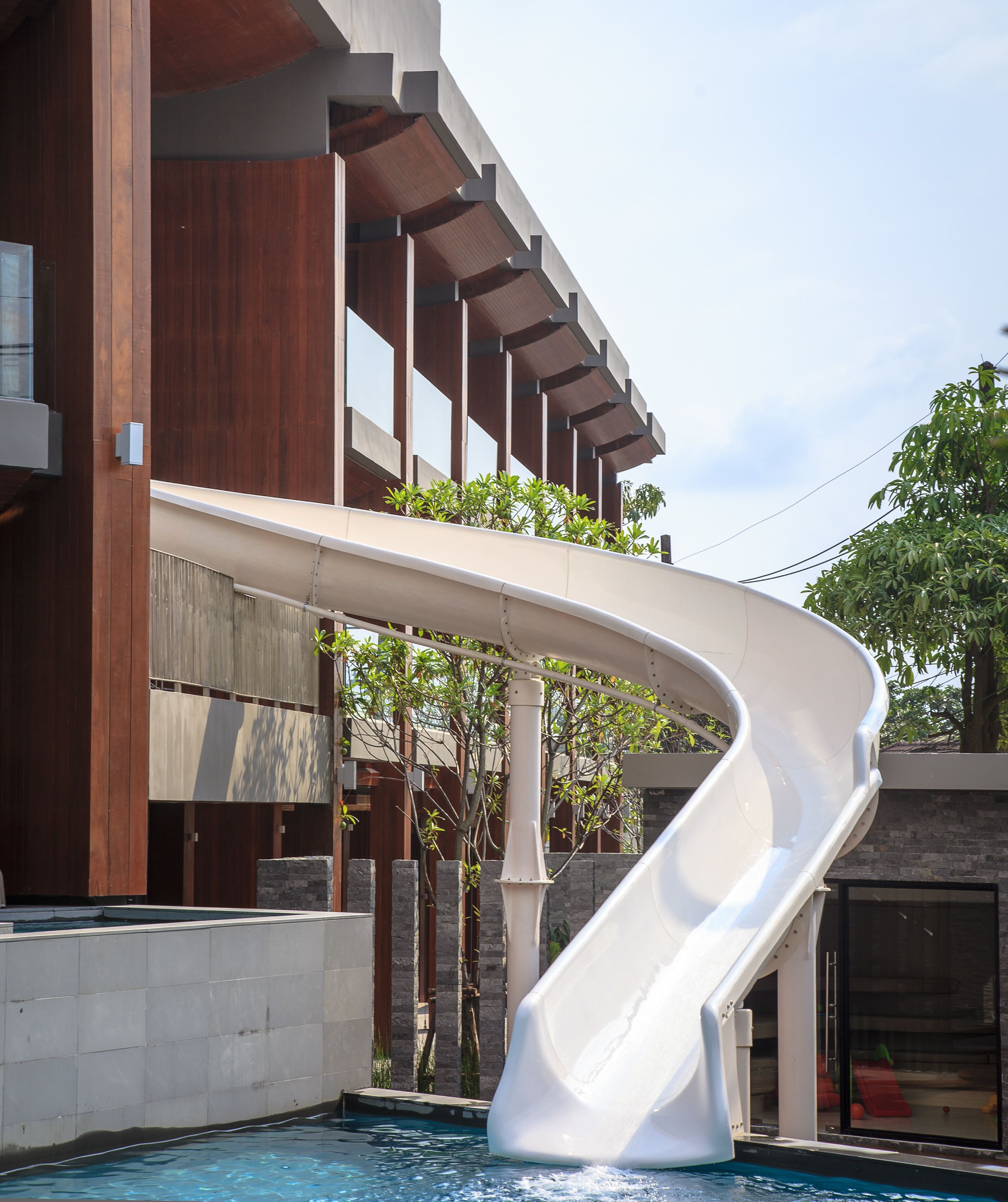 A modern building with a curved white slide over a pool.