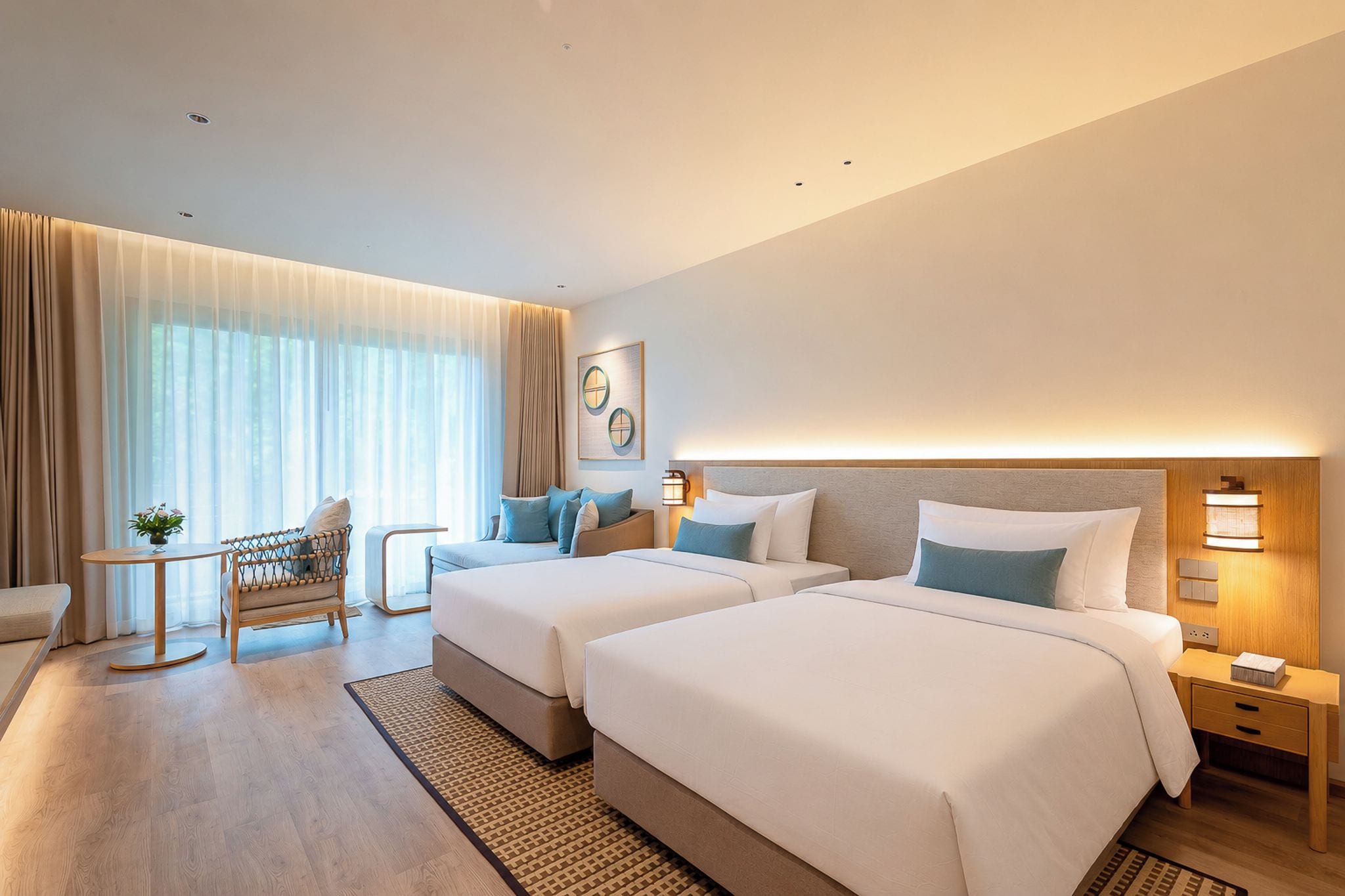 A hotel room with two beds, a seating area, and a small table.