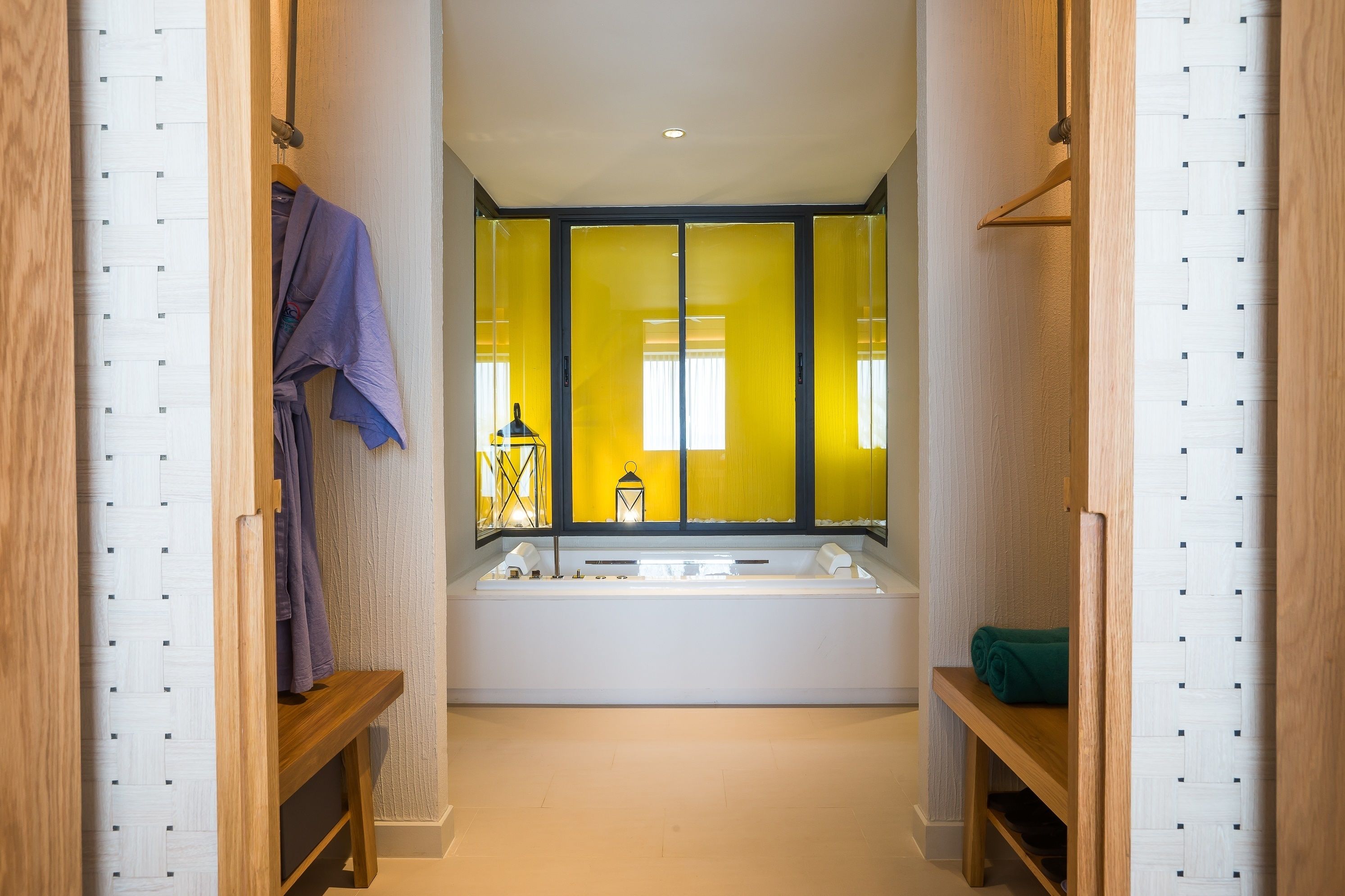 Ein modernes Badezimmer mit einer großen Badewanne, Holzregalen und einem Spiegel mit gelben Vorhängen.