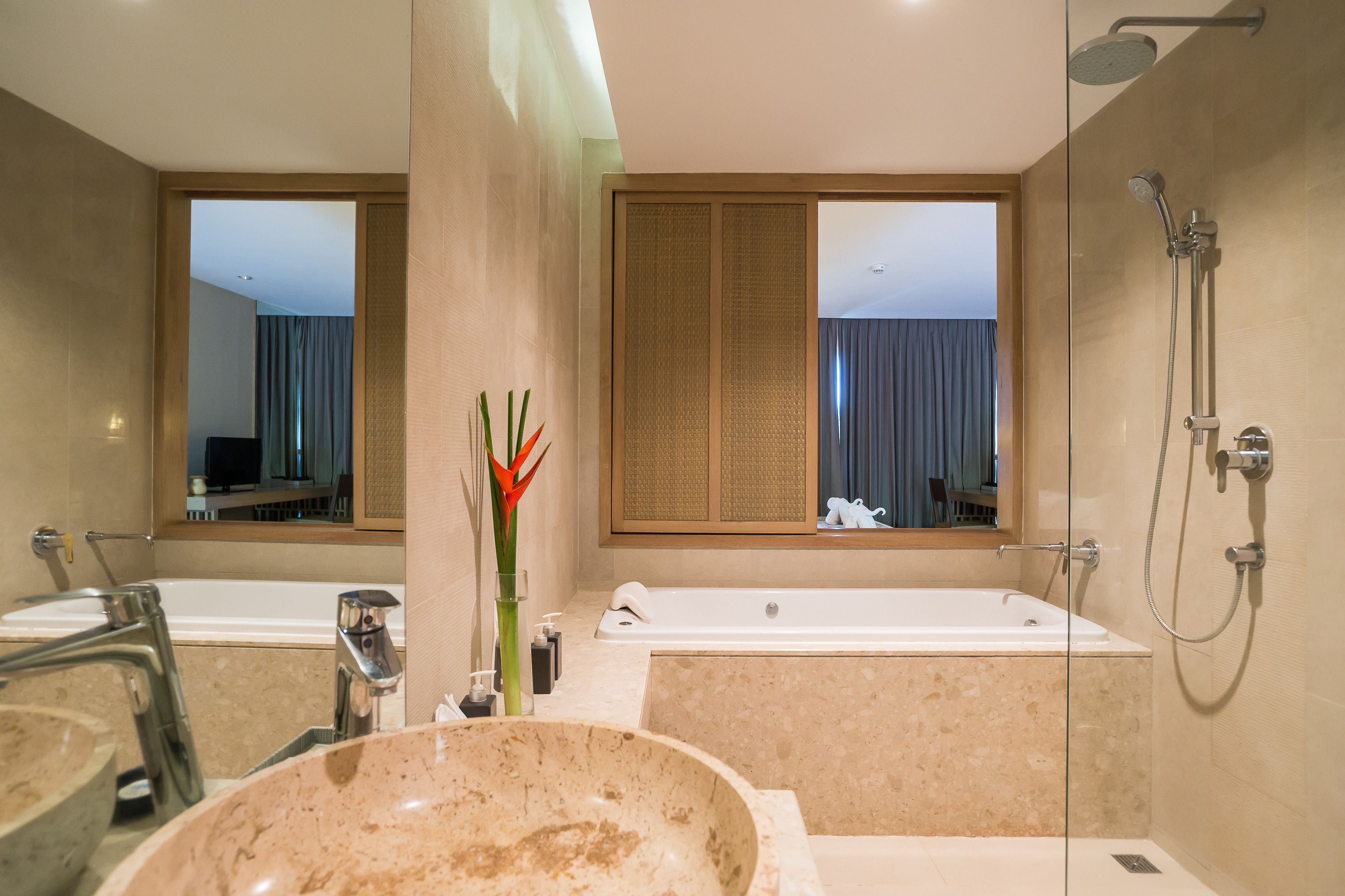 A modern bathroom with a large bathtub, a glass-enclosed shower, and a marble sink.