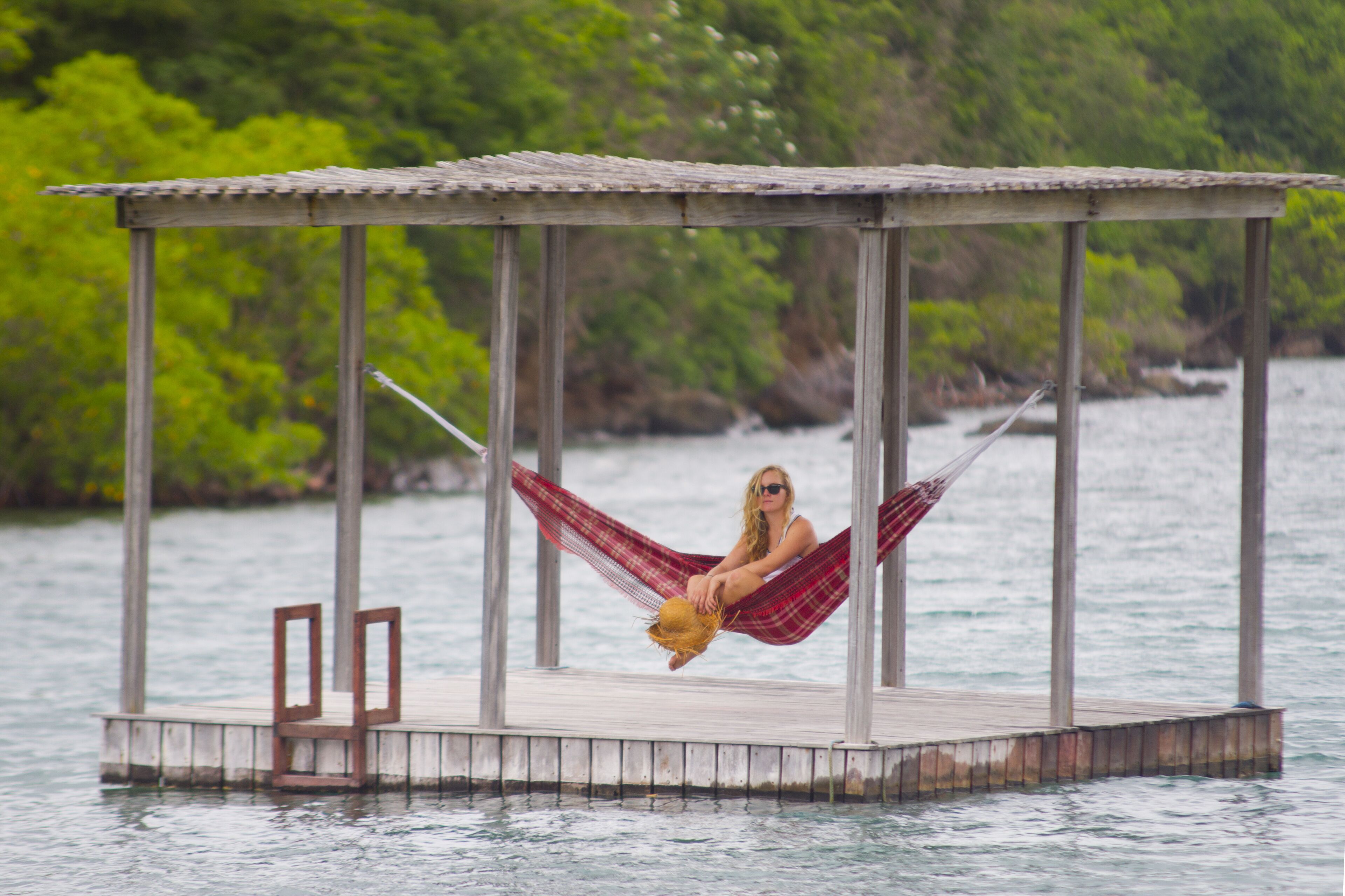 A wooden dock with a covered seating area and a hammock.