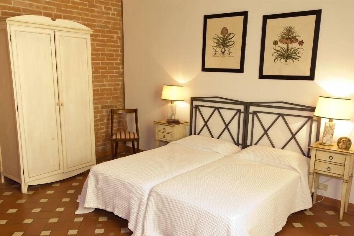 Une chambre avec deux lits, une armoire, une chaise et deux tables de chevet avec des lampes.