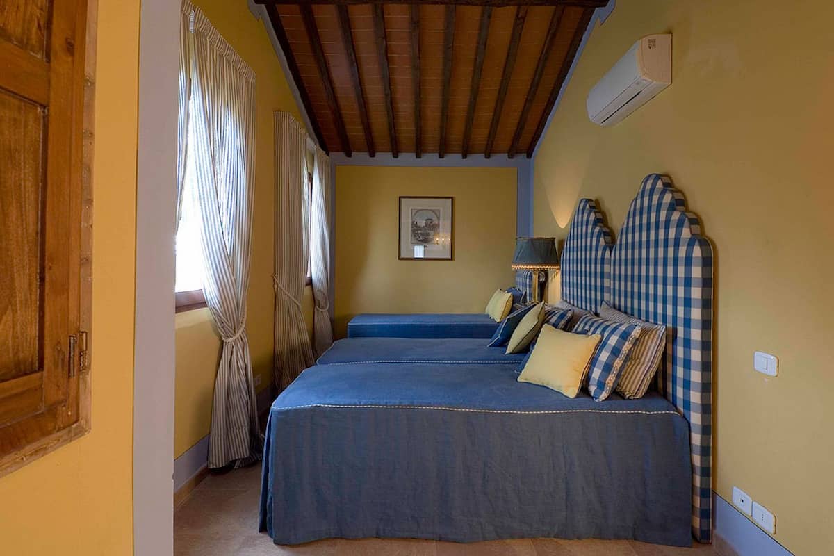 Une chambre avec deux lits, un plafond en bois et un tableau encadré au mur.