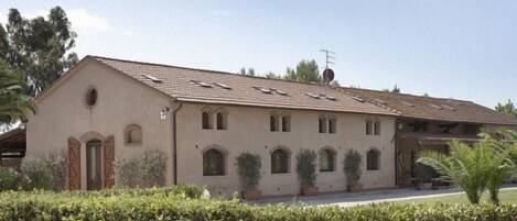 A two-story building with a flat roof, multiple windows, and a small satellite dish.