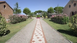 Un chemin menant à un bâtiment dont le sol est recouvert de carreaux et qui possède un mur en briques sur un de ses côtés.