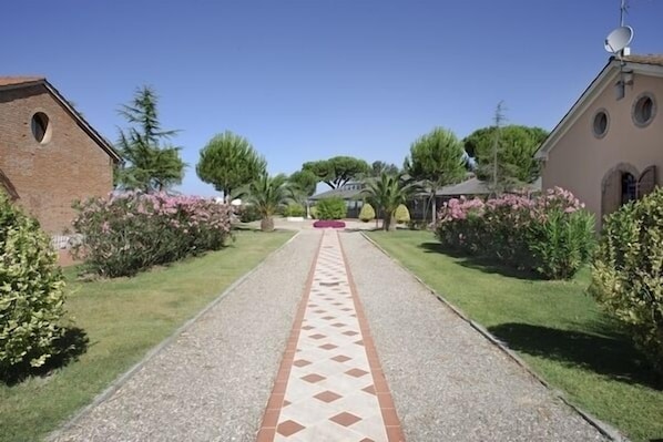 Un chemin menant à un bâtiment dont le sol est recouvert de carreaux et qui possède un mur en briques sur un de ses côtés.