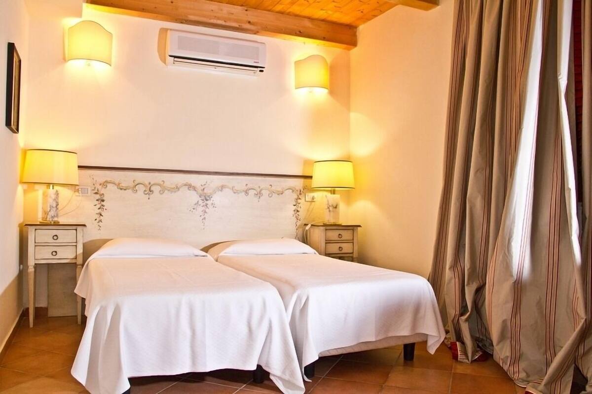 Une chambre avec deux lits, un plafond en bois et deux lampes de chevet.