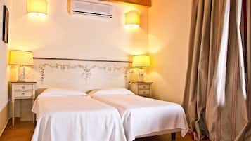 A bedroom with two beds, a wooden ceiling, and two bedside lamps.