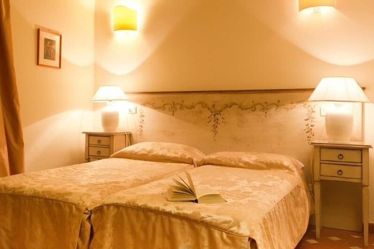 Une chambre d’hôtel avec un lit, deux lampes de chevet, une table de chevet et un tableau encadré au mur.