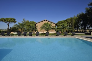 Une piscine avec des chaises longues et un bâtiment en arrière-plan.