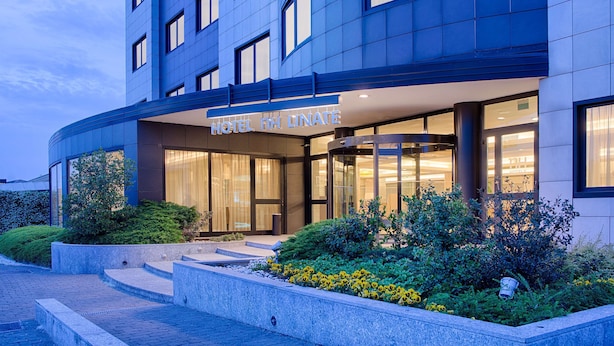 A modern hotel with a curved facade, large windows, and a well-lit entrance.