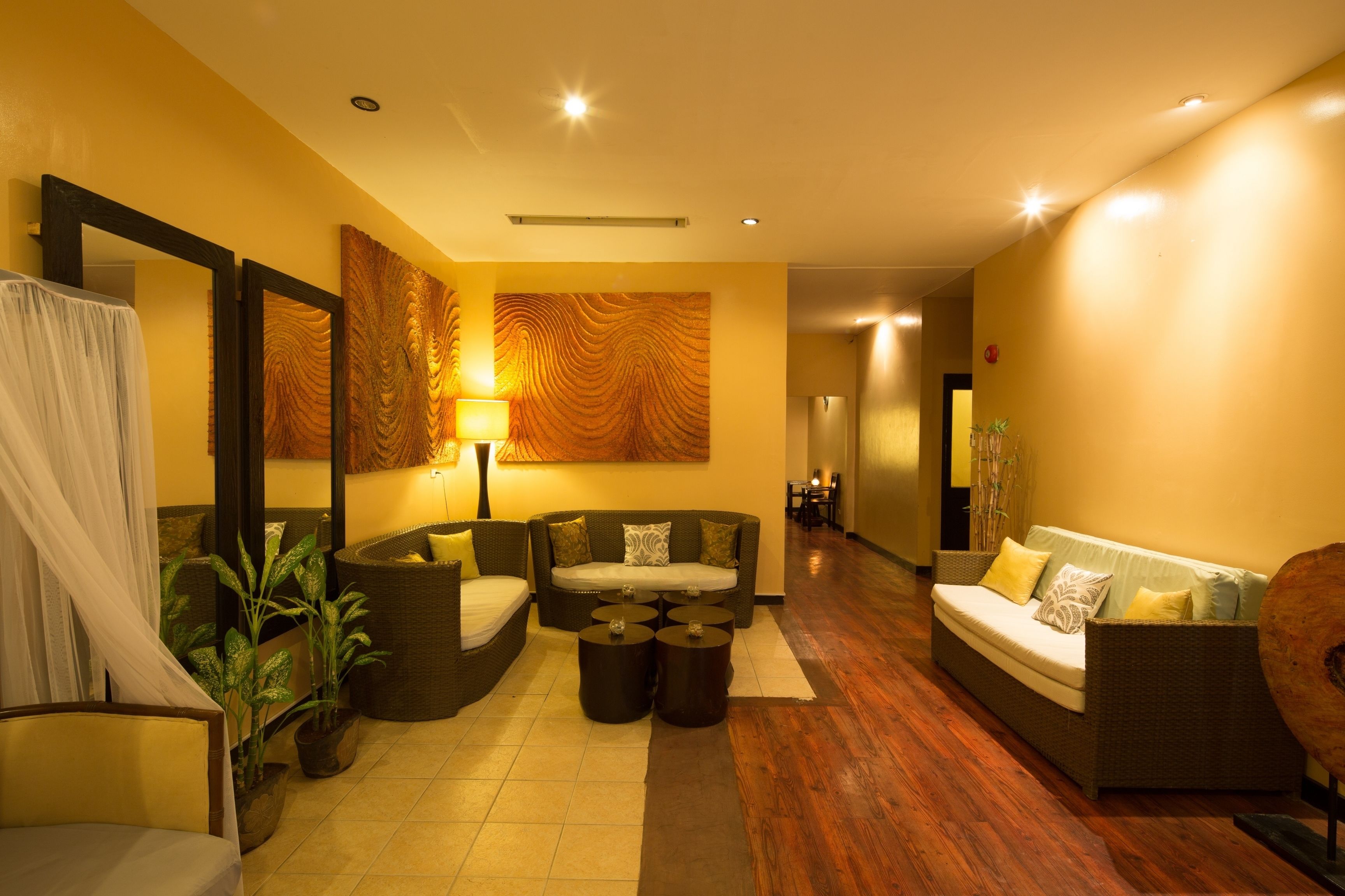 A modern hotel lobby with a sofa, chairs, a coffee table, and a large mirror.