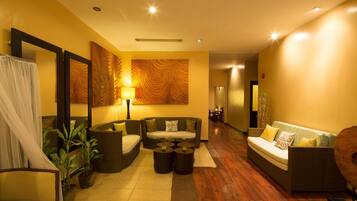 A modern hotel lobby with a sofa, chairs, a coffee table, and a large mirror.