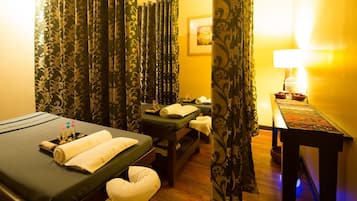 Relax in a serene spa room with two massage tables, a wooden bench, and a cozy reading nook.