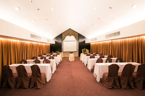 Un salón de conferencias con mesas y sillas dispuestas para una reunión.