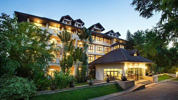 Un hôtel à plusieurs étages, doté d’une entrée bien éclairée et d’un petit bâtiment annexe.
