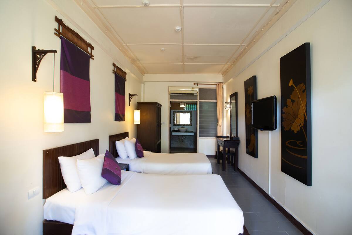 A hotel room with two beds, a television, and artwork on the walls.