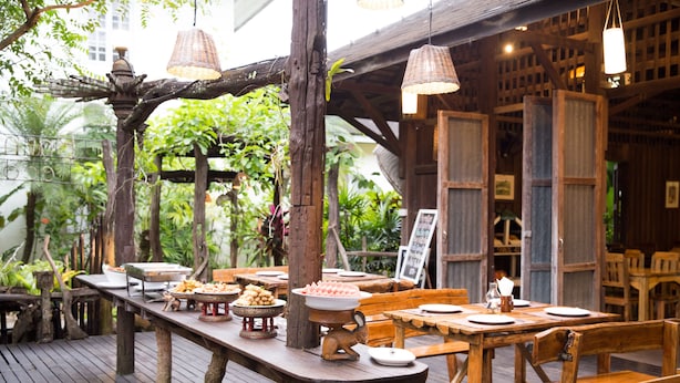 An outdoor wooden deck with tables set for dining, surrounded by lush greenery and wooden structures. - Eco Resort Chiang Mai (Chiang Mai)