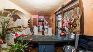 A hotel lobby with a reception desk, seating area, and a television screen. - Hotel Al Ritrovo (Piazza Armerina)