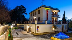 A two-story hotel with a balcony on the upper floor, a well-lit entrance, and a pool area with a glass enclosure. - Hotel Al Ritrovo (Piazza Armerina)