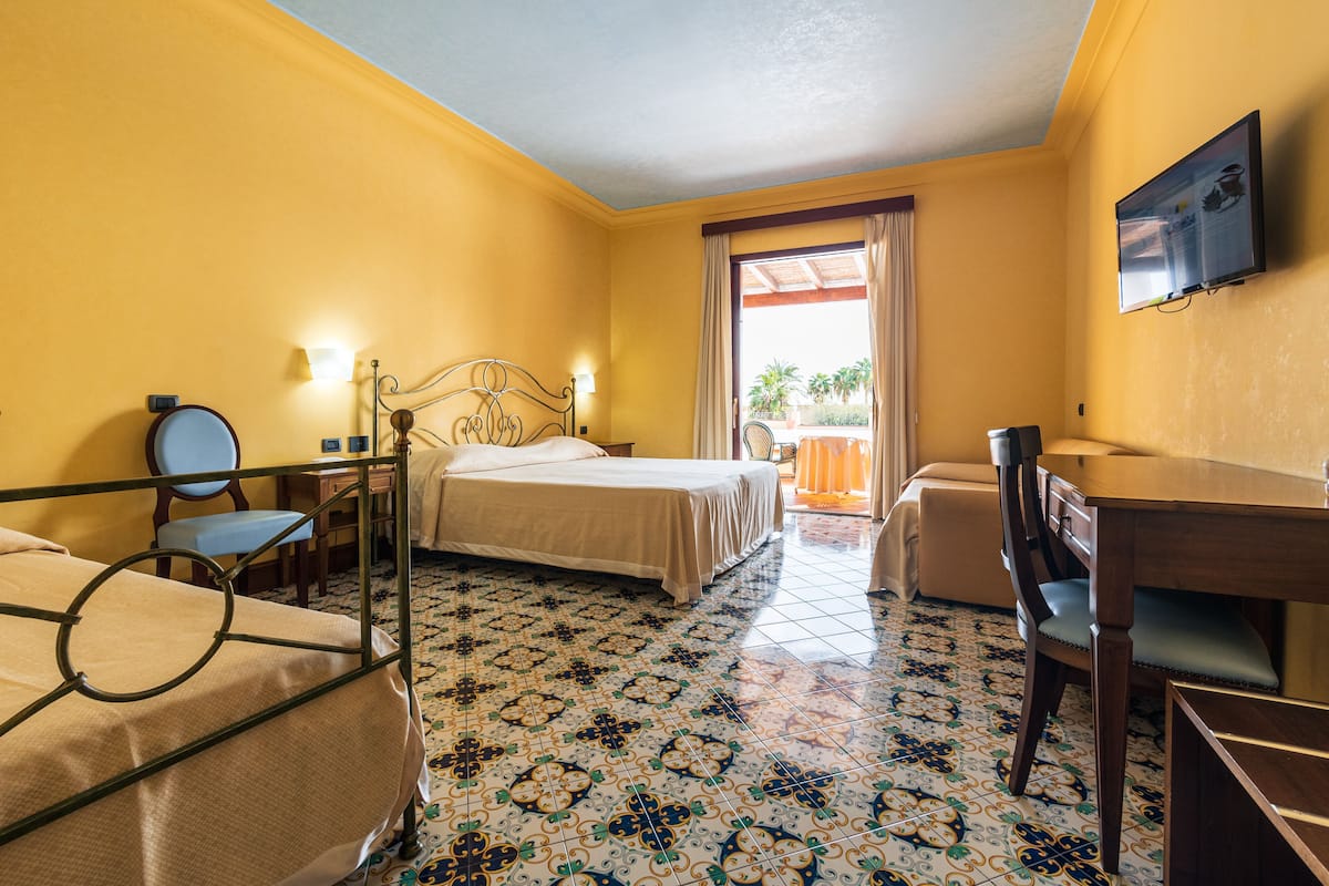 A hotel room with a bed, a desk, a chair, and a television.