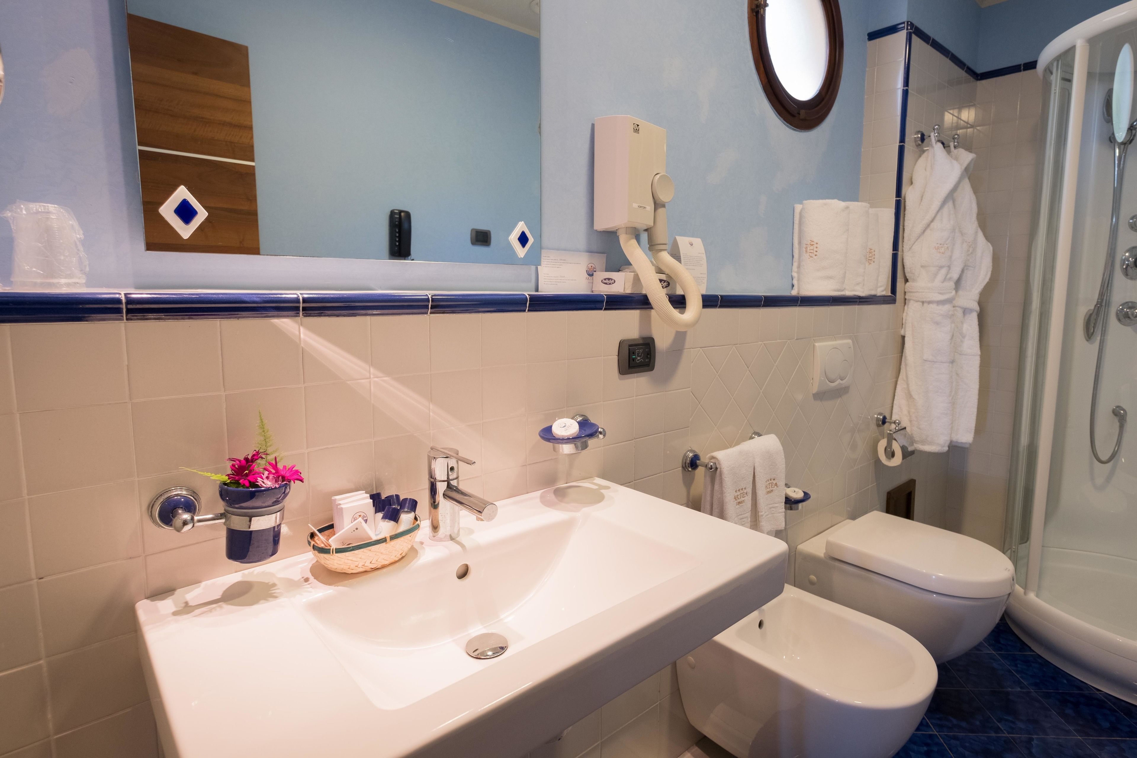 Baño con lavamanos, dos inodoros, ducha y espejo.