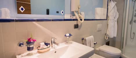 Baño con lavamanos, dos inodoros, ducha y espejo.