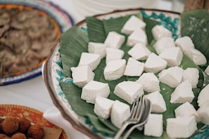 A plate of white cubes on a banana leaf with a fork beside it.