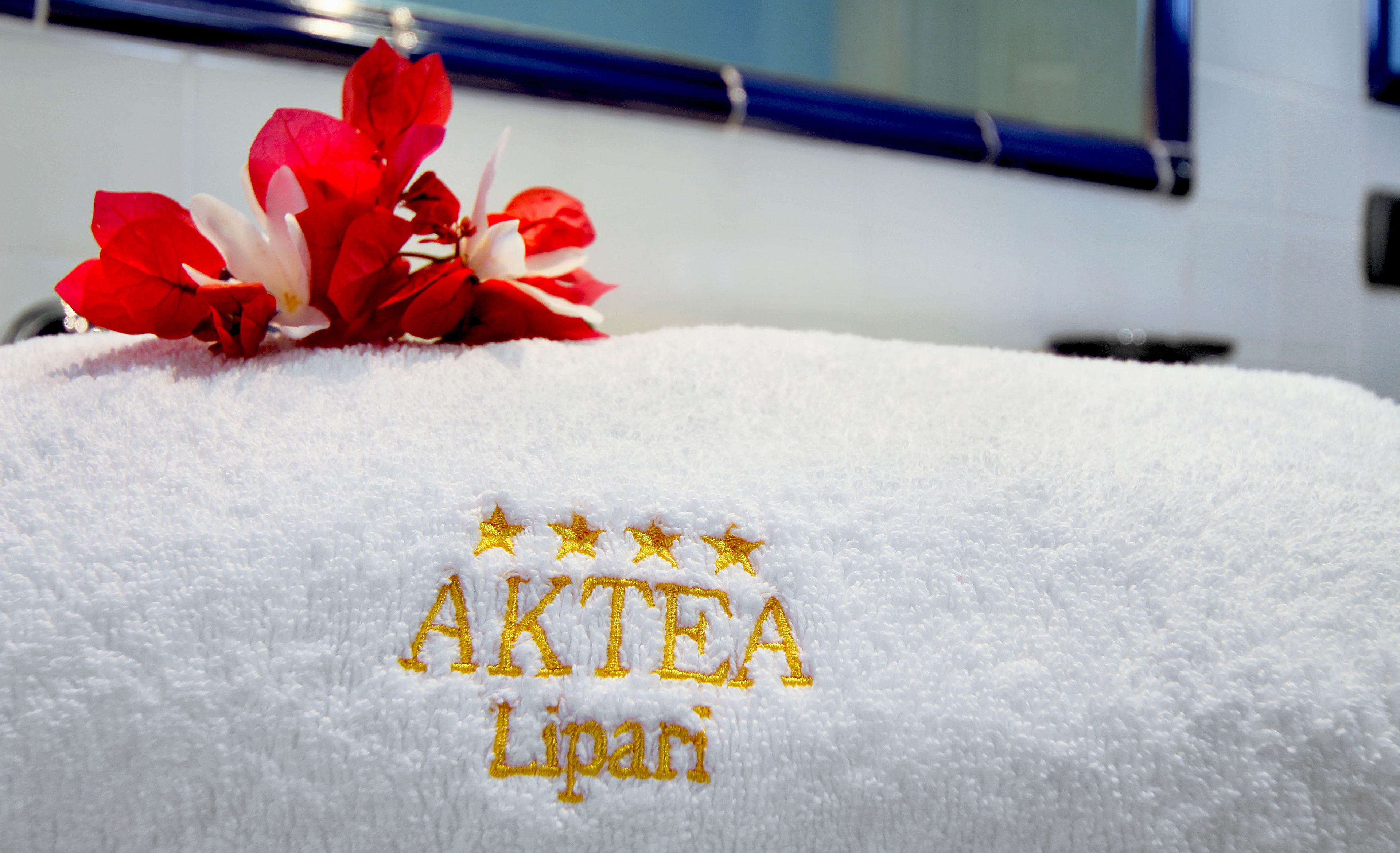 Ein weißes Handtuch mit eingesticktem Text "AKTEA Lipari" und drei Sternen darüber.