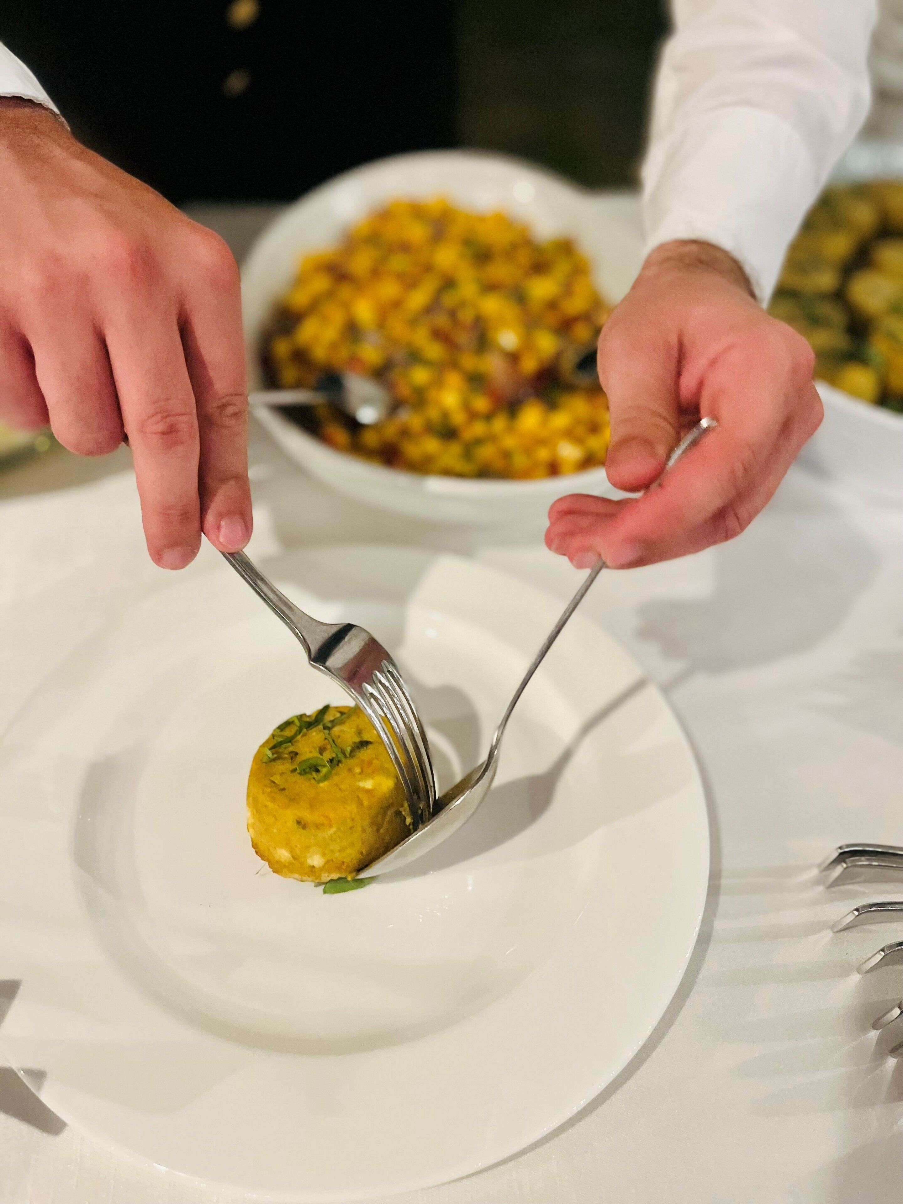 Une personne servant un plat de couleur jaune dans une assiette blanche.