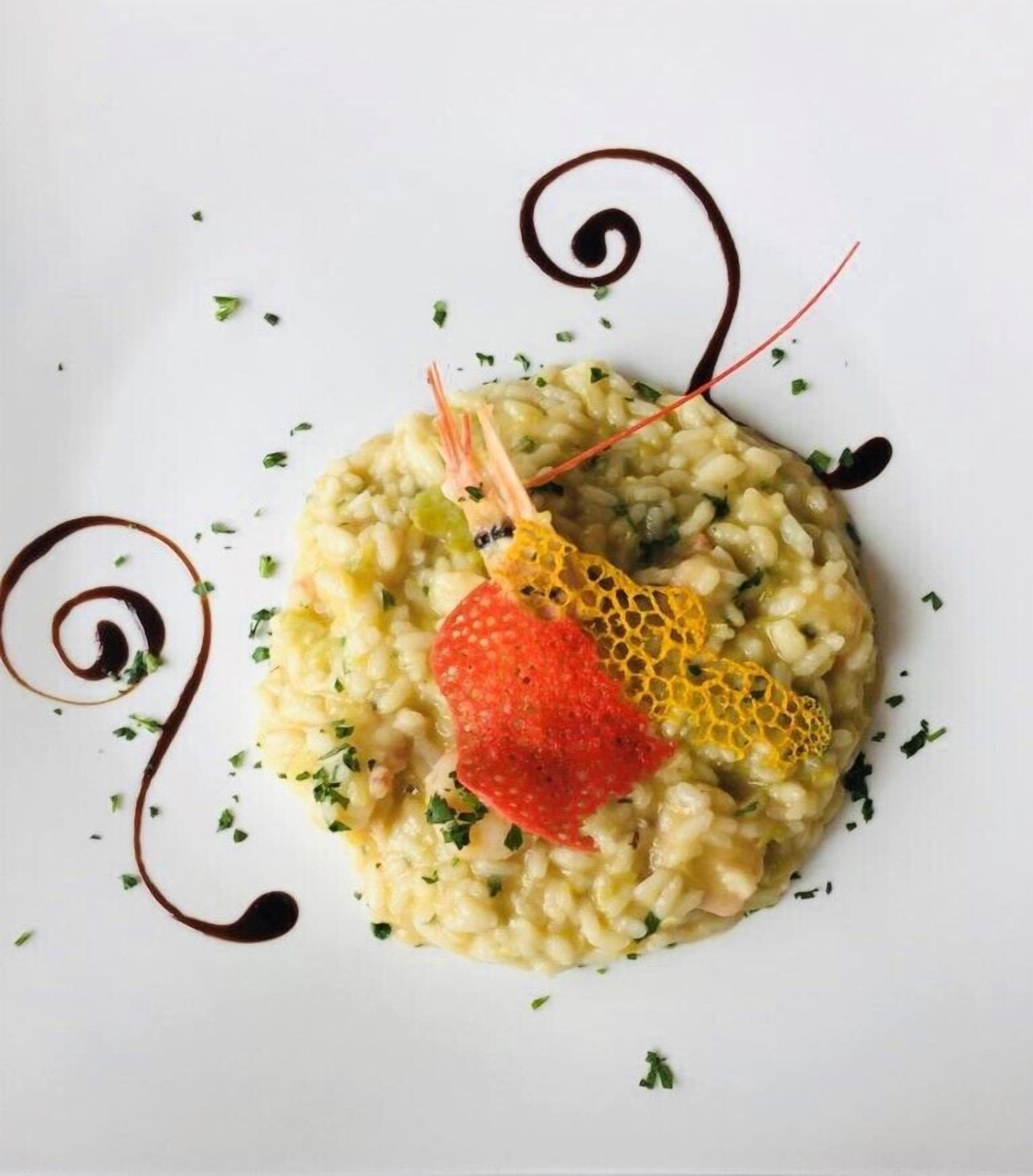 Eine Portion Risotto mit einer Garnele und einer Dekoration.