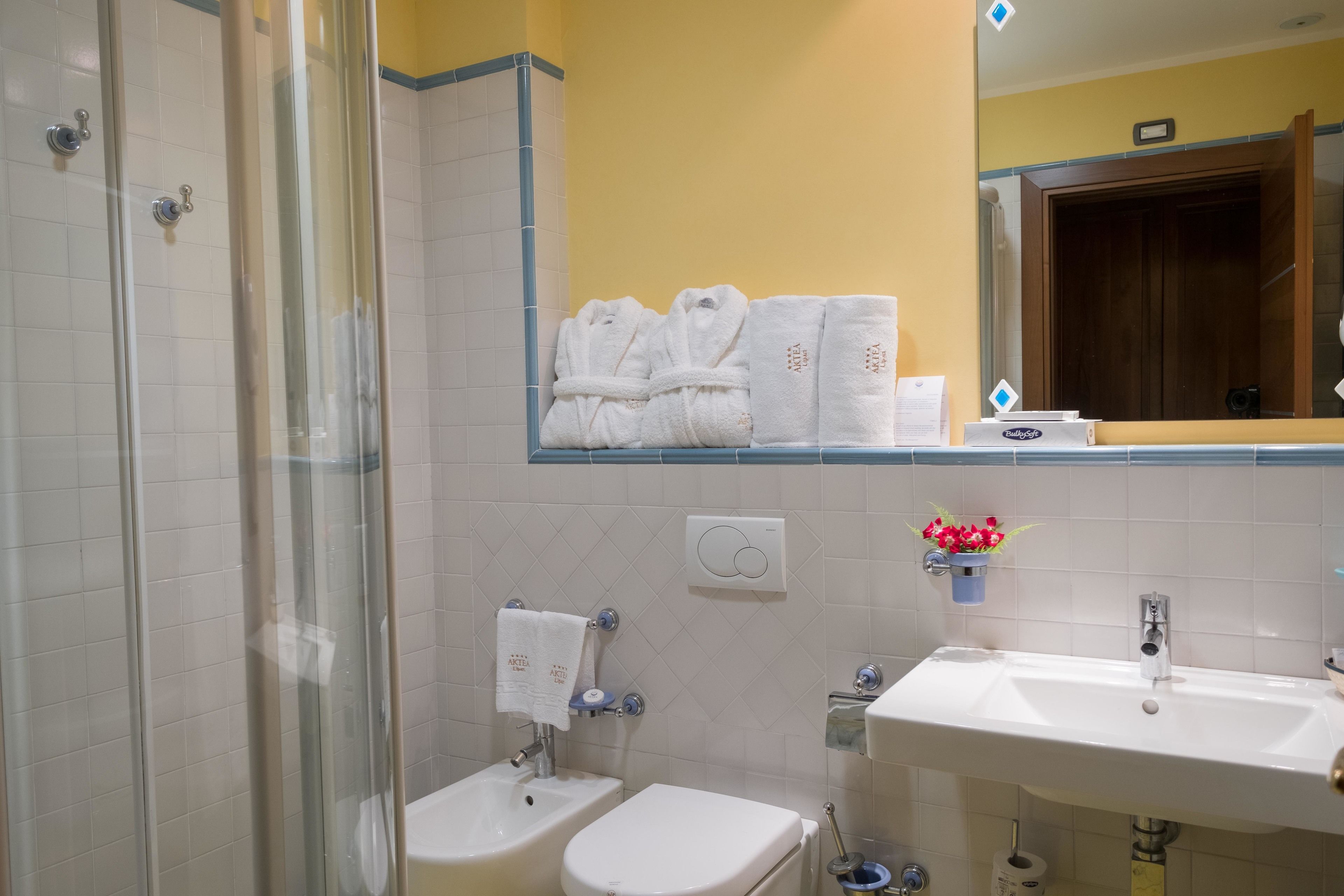 Ein Badezimmer mit Duschkabine aus Glas, einem Bidet, einer Toilette und einem Waschbecken mit Spiegel darüber.