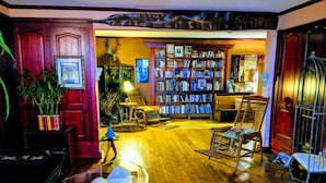 A cozy living room with a wooden floor, a bookshelf, a chair, and a table with a glass top.