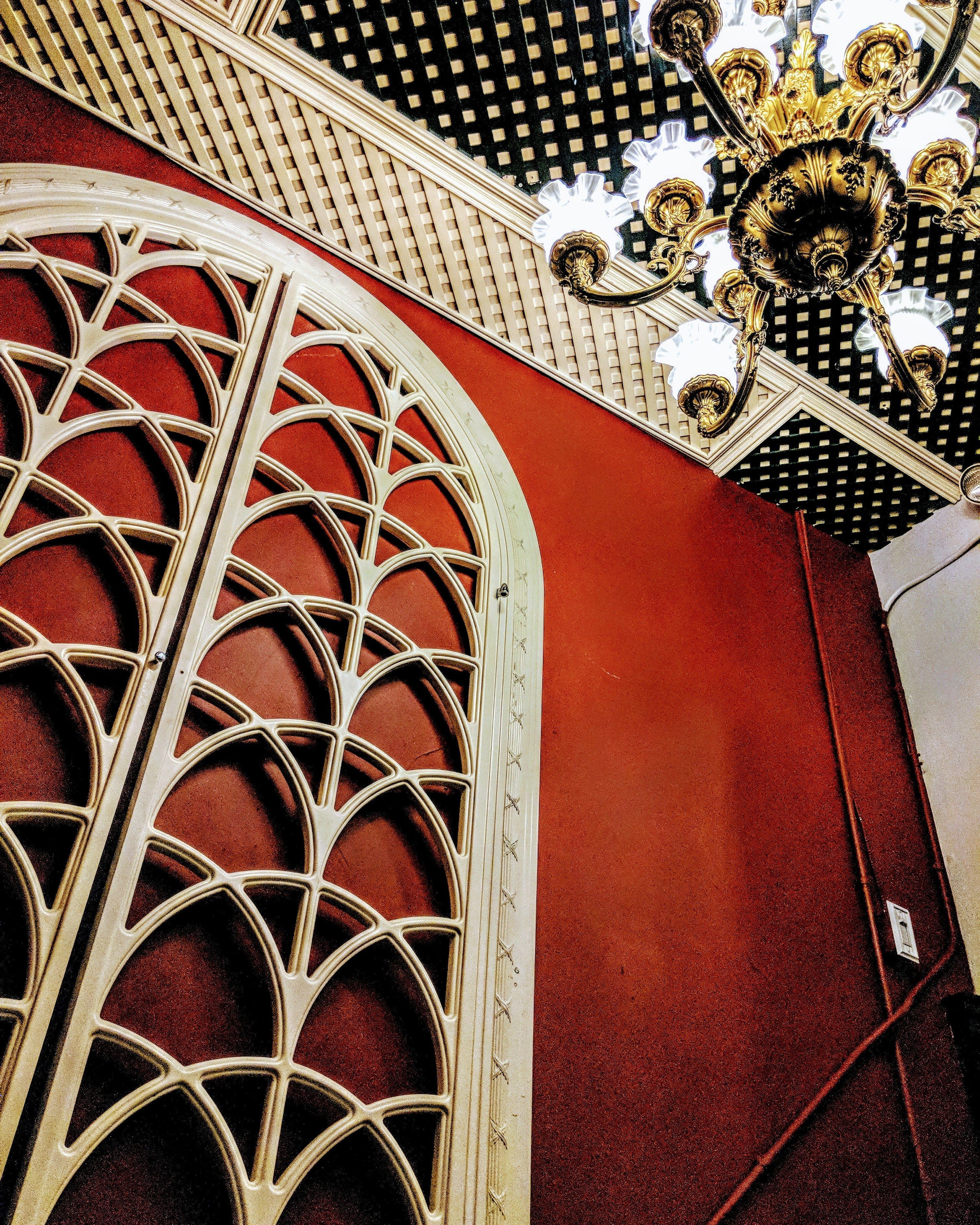 A ceiling with a decorative wrought iron grille and a chandelier.