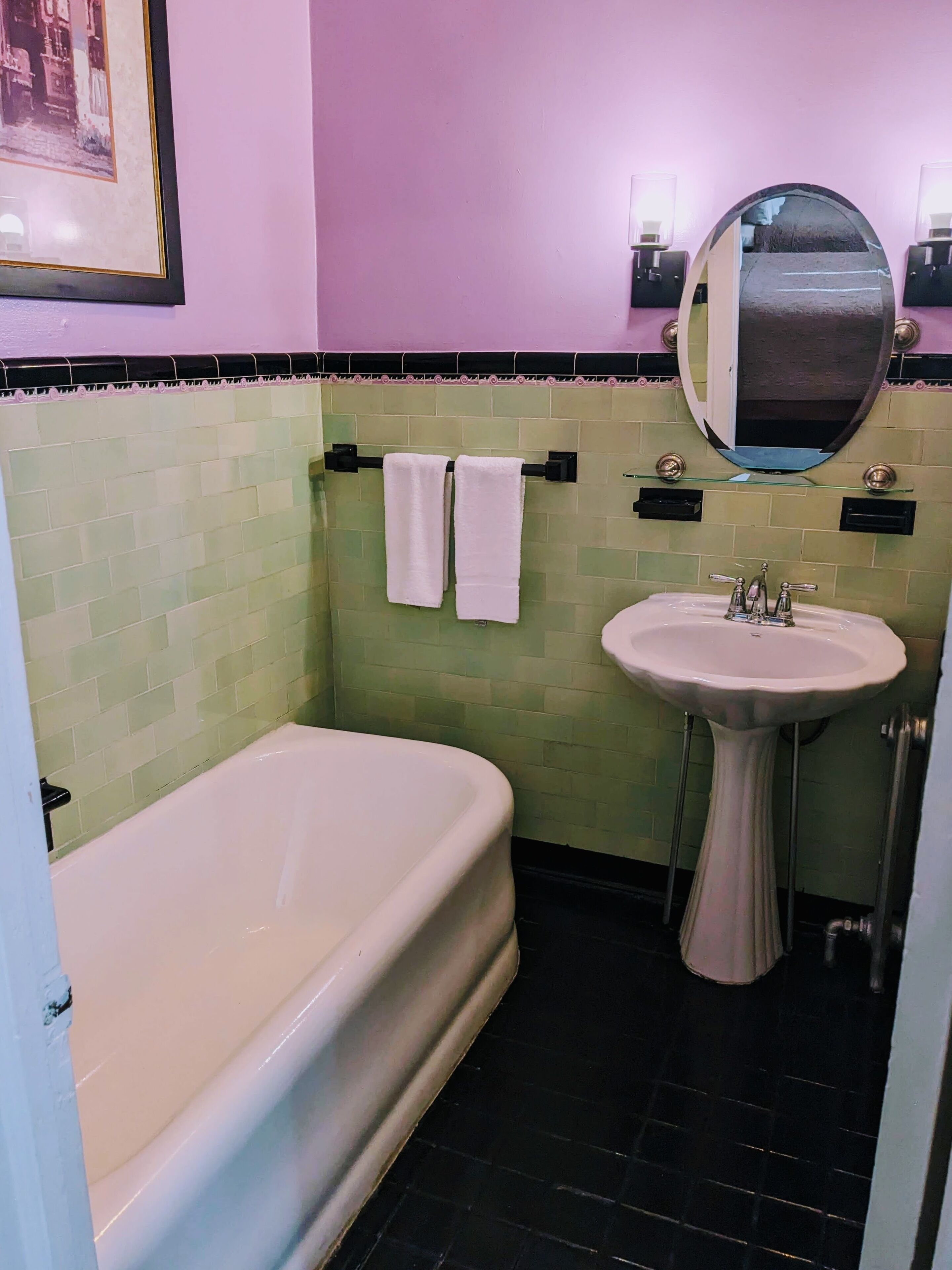 A bathroom with a bathtub, a pedestal sink, and a wall-mounted mirror.